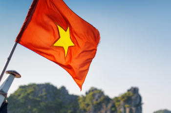 Vietnamese flag waving against the backdrop of Ha Long Bay's limestone karsts