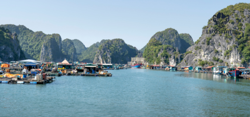 Floating village in Ha Long Bay with limestone karsts in the background and various boats and floating houses on the water