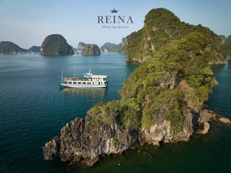 The Reina cruise ship sailing among the beautiful small rock islands in Halong Bay, showcasing the stunning natural beauty of the area