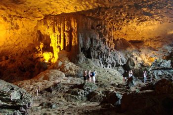 Visitors exploring the illuminated interior of Sung Sot Cave in Halong Bay, showcasing stunning stalactites and rock formations