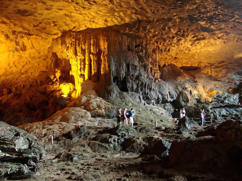 Visitors exploring the illuminated interior of Sung Sot Cave in Halong Bay, showcasing stunning stalactites and rock formations
