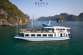 The Reina day cruise boat sailing in the serene waters of Halong Bay, surrounded by lush, rocky islands