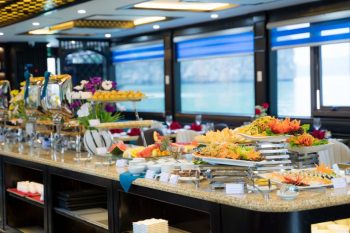 Colorful buffet setup with fresh fruits and dishes on La Casta luxury cruise in Ha Long Bay.