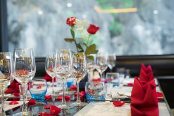 Elegant table setup with wine glasses and red napkins on La Casta luxury cruise in Ha Long Bay.