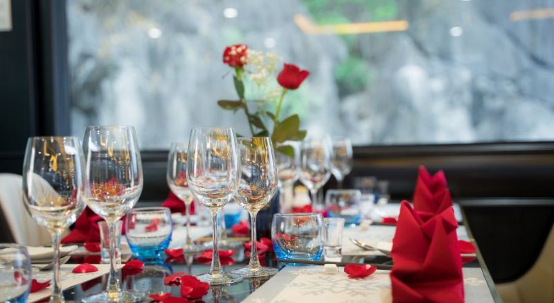 Elegant table setup with wine glasses and red napkins on La Casta luxury cruise in Ha Long Bay.