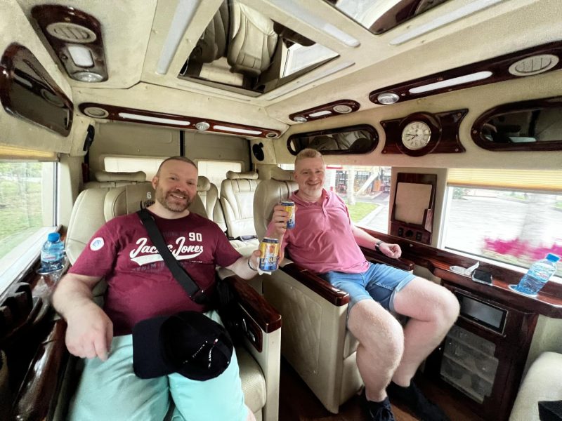 Two happy tourists enjoying the luxurious interior of a limousine van on a Hanoi to Ha Long Bay tour
