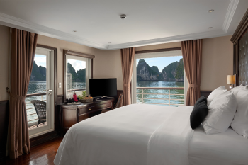 Luxurious cabin on the Paradise Elegance Cruise with a king-size bed, elegant furnishings, and panoramic views of Ha Long Bay