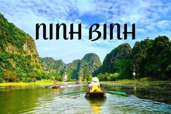 Scenic view of Ninh Binh with a boat rowing through lush green landscapes and limestone karsts under a blue sky