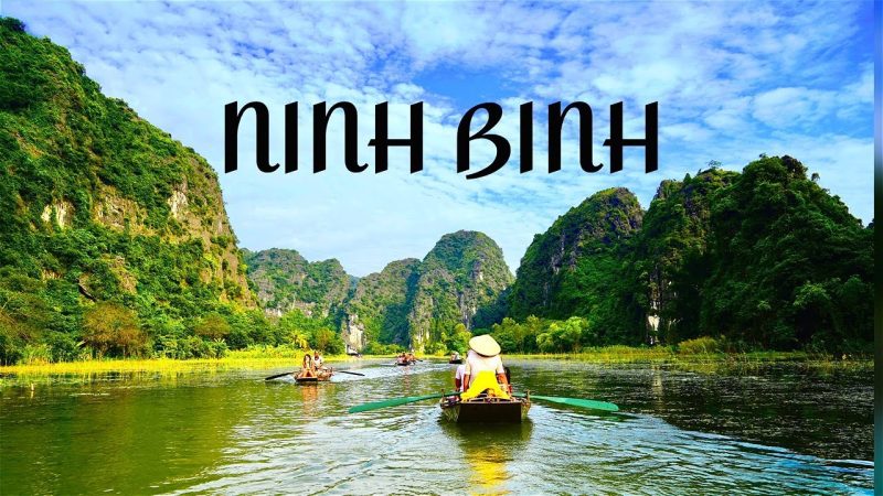 Scenic view of Ninh Binh with a boat rowing through lush green landscapes and limestone karsts under a blue sky
