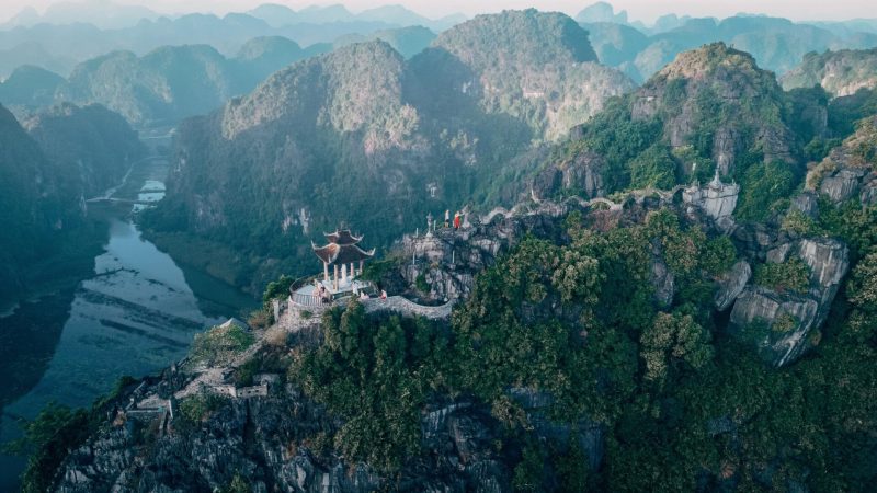 Aerial view of the majestic karst mountains and ancient temples of Ninh Binh, Vietnam, shrouded in mist and lush greenery
