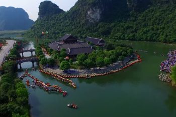 Aerial view of Trang An in Ninh Binh with traditional boats on the river, lush green mountains, and ancient temples