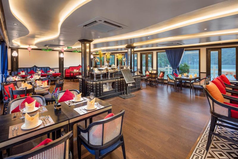 Interior view of a luxurious dining area on Verdure Lotus Cruise in Ha Long Bay with elegant decor and large windows offering scenic views.