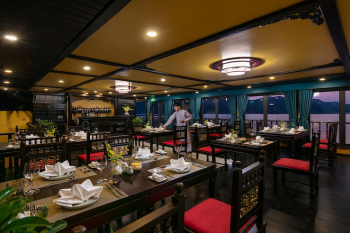Elegant dining area on Nostalgia Cruise with a view of Ha Long Bay at sunset