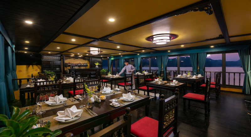 Elegant dining area on Nostalgia Cruise with a view of Ha Long Bay at sunset