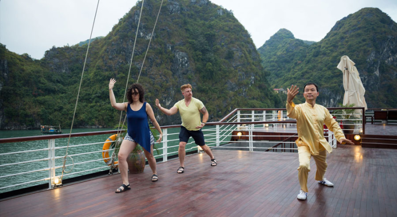 Guests practicing Tai Chi on the deck of Orchid Classic Cruise in Ha Long Bay