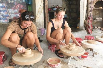 Visitors crafting ceramics and lacquer paintings at Bat Trang village, showcasing traditional Vietnamese arts.