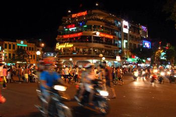 Tourists enjoying the view at the Shark Jaw Building in Hanoi, experiencing the vibrant nightlife and cityscape.