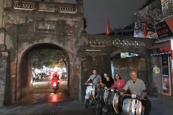 Tourists taking photos at the ancient city gate in Hanoi, experiencing the historic sites and vibrant nightlife.