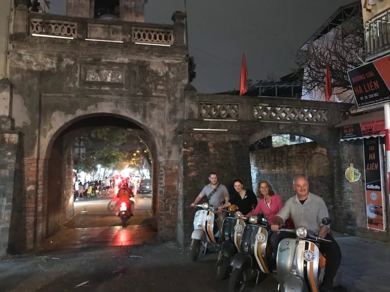 Tourists taking photos at the ancient city gate in Hanoi, experiencing the historic sites and vibrant nightlife.