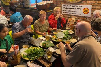 Tourists enjoying banh xeo rolls in Hanoi, experiencing the local cuisine and nightlife.