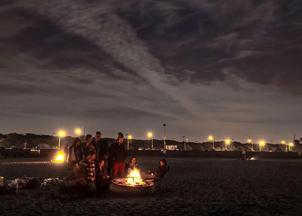 Tourists enjoying a beach bonfire at night in Ha Long Bay