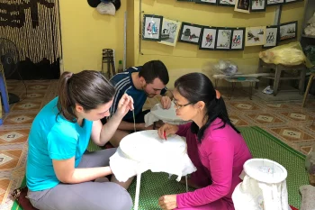 Tourists learning embroidery at Van Long Natural Reserve, experiencing traditional Vietnamese crafts.