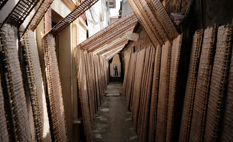 Traditional bamboo weaving in a narrow alley at Tho Ha village, showcasing Vietnamese handicraft culture.
