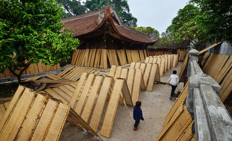 Traditional bamboo weaving in a narrow alley at Tho Ha village, showcasing Vietnamese handicraft culture.